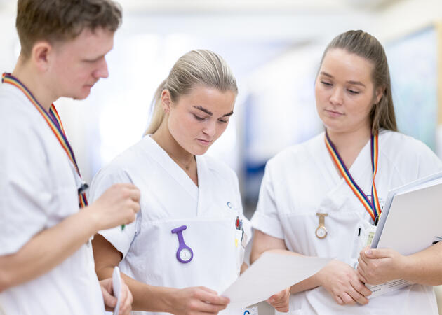 Tre sykepleiere i hvit uniform. To jenter og en gutt.