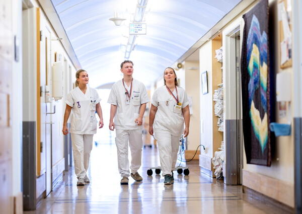 Tre sykepleiere i sykehuskorridor