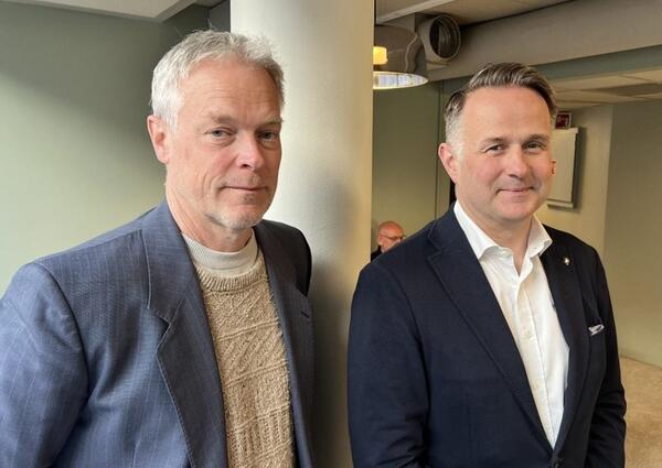 To med med dressjakke ser mot fotografen.