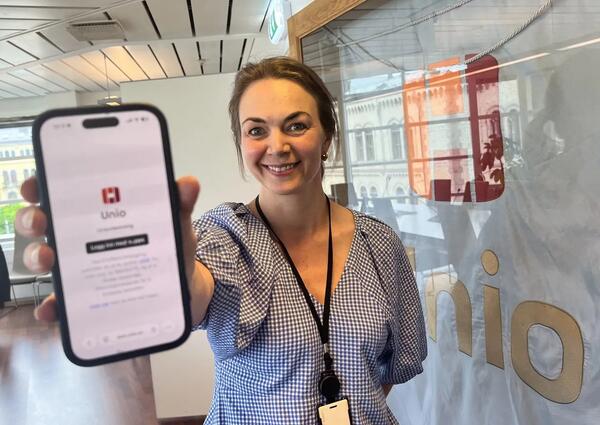 En smilende kvinne viser frem en mobilskjerm der man ser Unio-logoen.