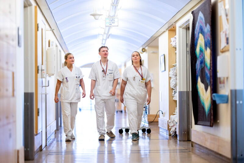 Tre sykepleiere i sykehuskorridor