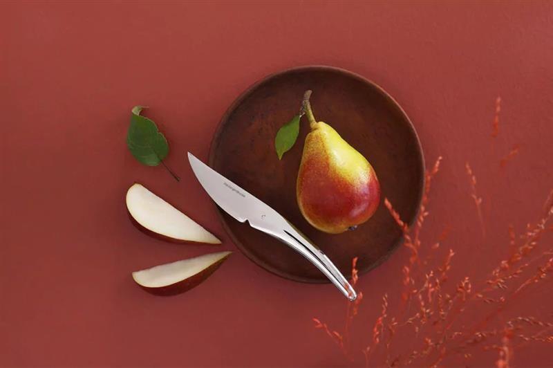 En kniv ligger på et fat sammen med en oppkuttet pære.