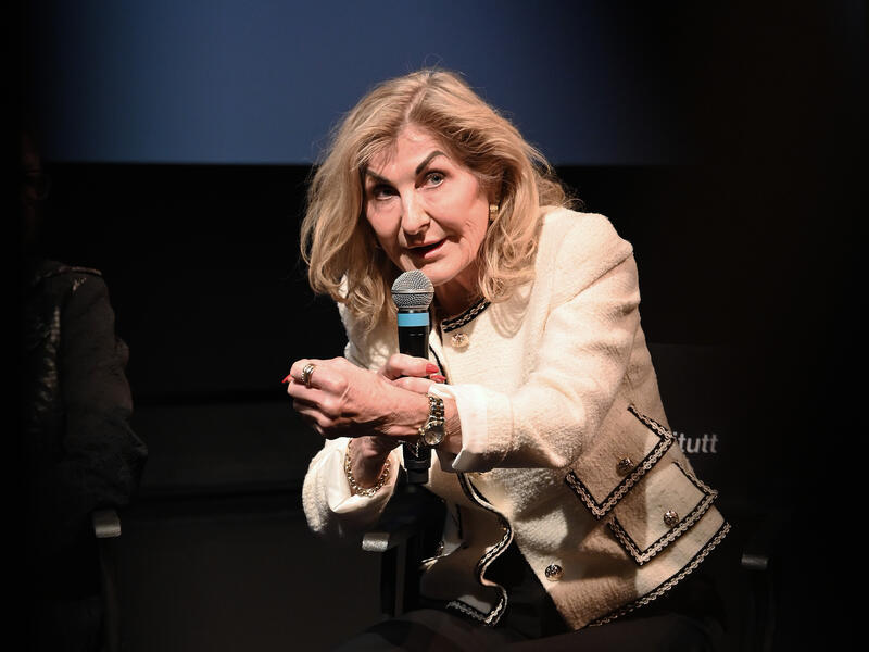 Kvinne snakker i telefon og gestikulerer.