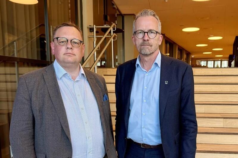 To menn med briller og dress står ved siden av hverandre