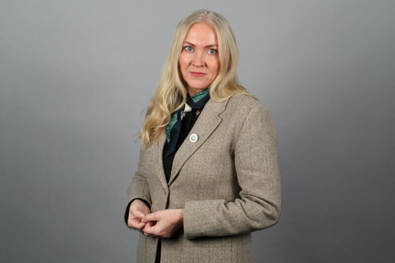 Portrettbilde av alvorlig kvinne med blazer og langt blondt hår.