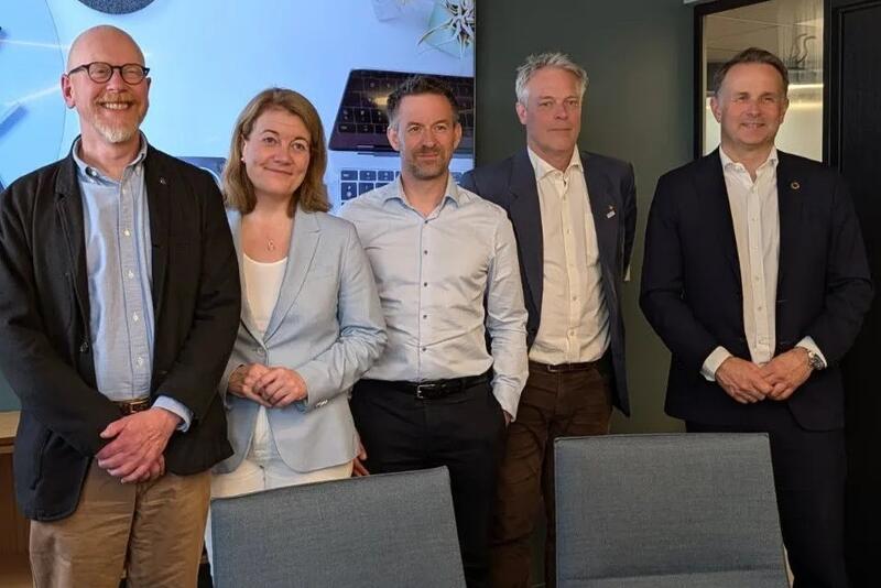 Fem voksne mennesker står ved siden av hverandre og ser mot fotografen.
