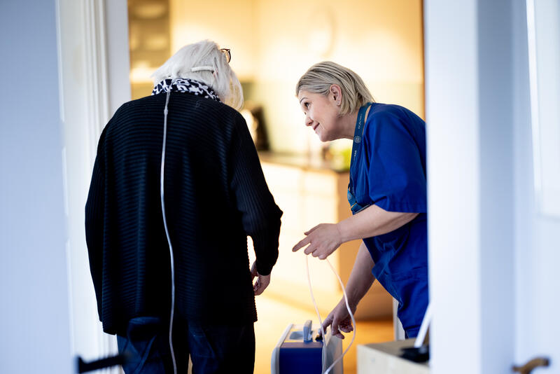 Sykepleier som hjelper en eldre pasient.