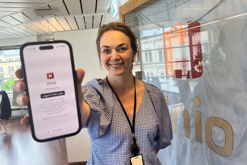 En smilende kvinne viser frem en mobilskjerm der man ser Unio-logoen.